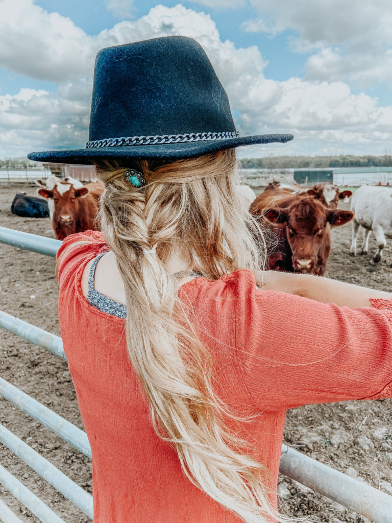 a blonde girl (Kiersten Zile) looking off into the cattle pasture with a turquoise jewelry piece in her braided half up hair