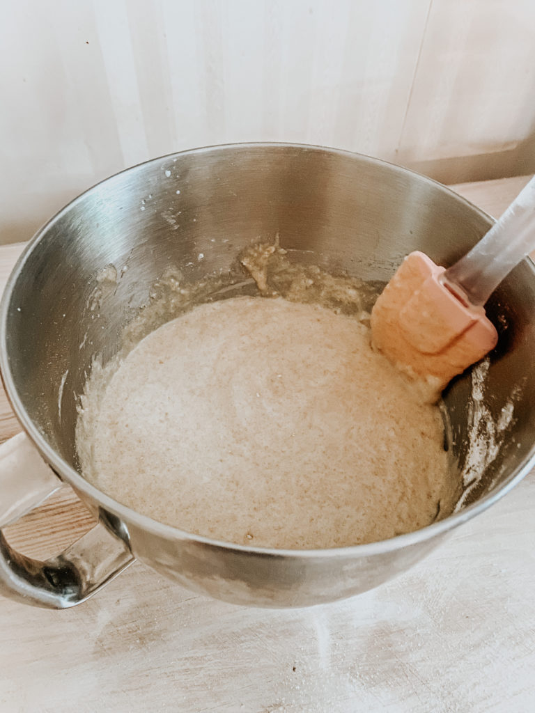 adding einkorn flour to the kitchenaid mixing bowl and stirring by hand