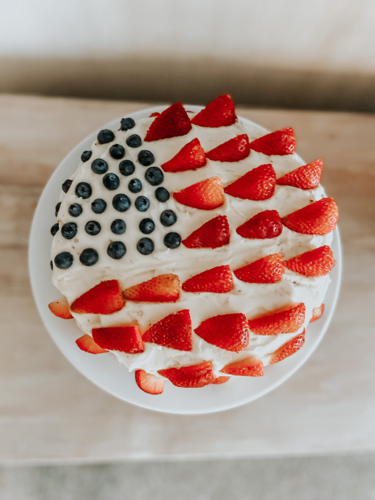 a double layered vanilla einkorn cake with strawberries and blueberries in the shape of an American flag 