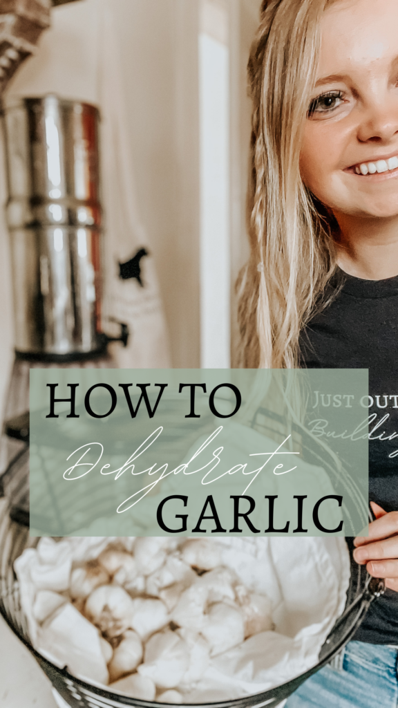 kiersten zile holding a garden basket of fresh garlic from a garden with a t shirt that says just out here building soil prepping to dehydrate garlic