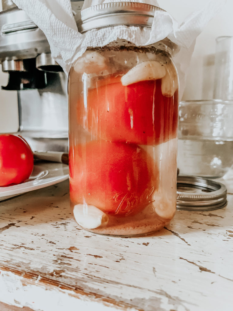 tomatoes in a mason jar with spices ready to make fermented tomatoes