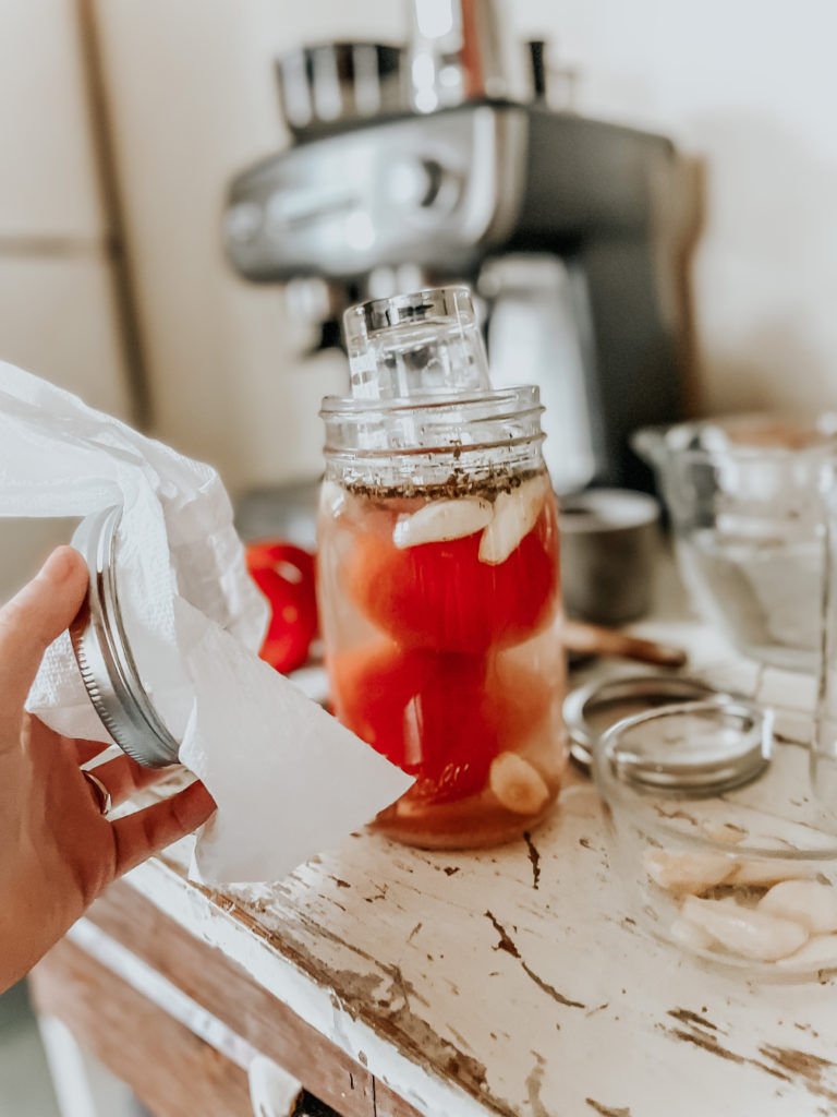 tomatoes in a jar with a fermentation weight ready to ferment to make fermented tomatoes