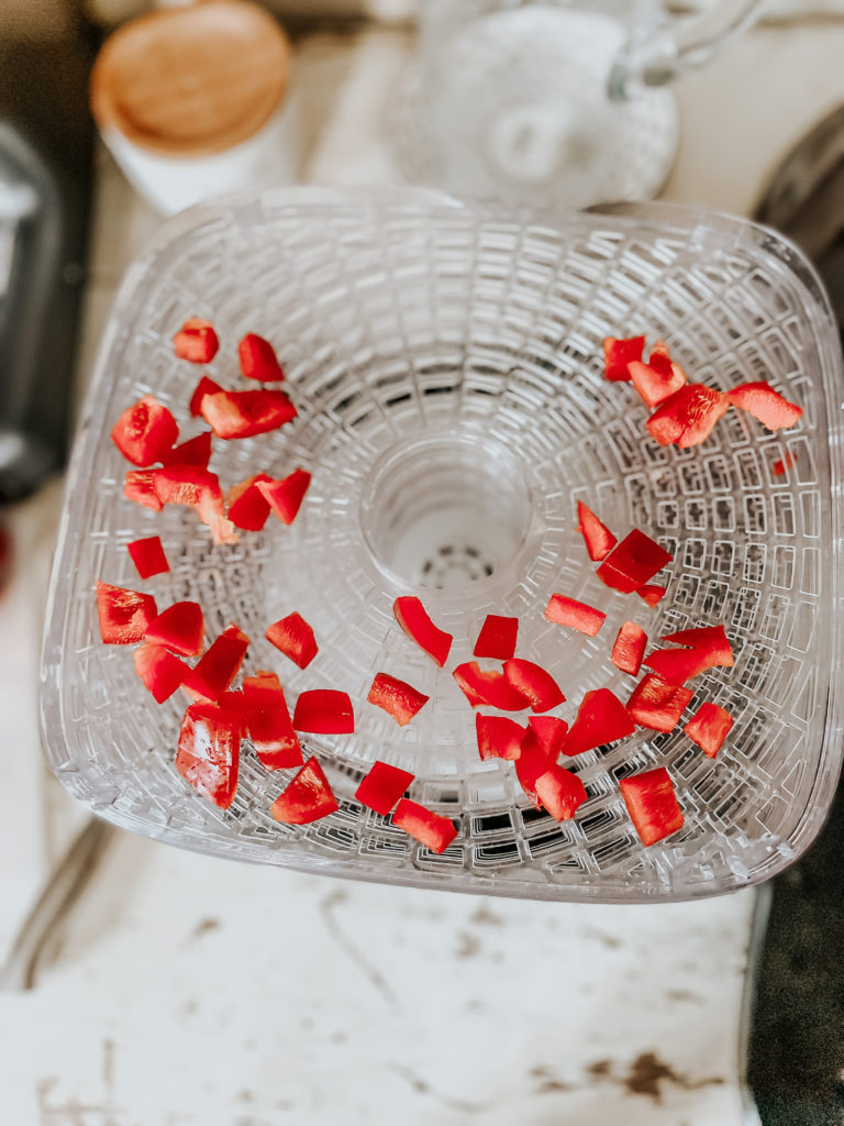 red sliced bell peppers on a dehydrator tray