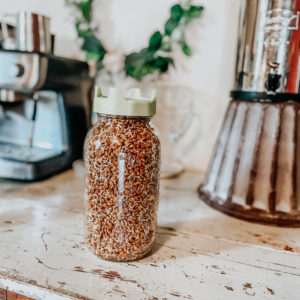lentil sprouts in a jar with a farmhouse display in the background sitting on a chipped paint table with a berkey water filter in the background