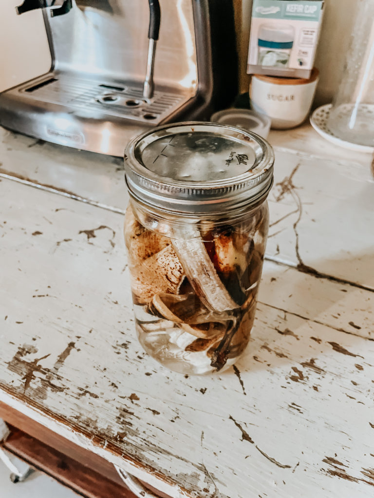 banana peels in a mason jar with water fermenting to banana peel fertilizer on a table with chipped paint