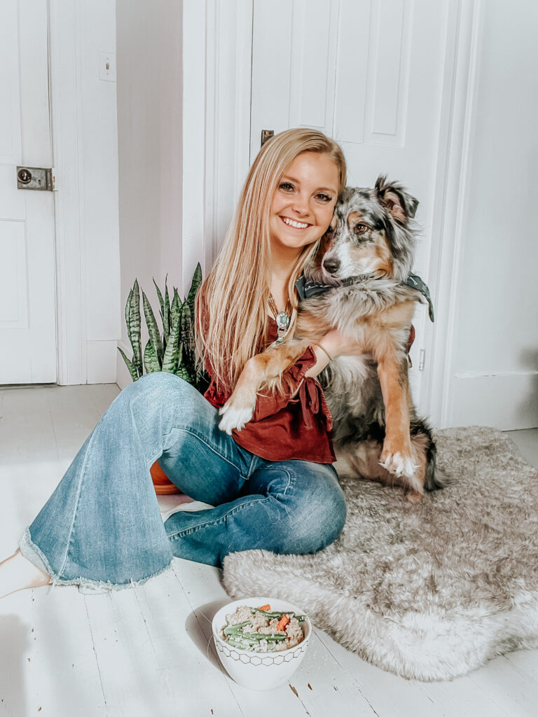 kiersten zile and her australian shepherd dog lexi together sitting with homemade dog food in front of them