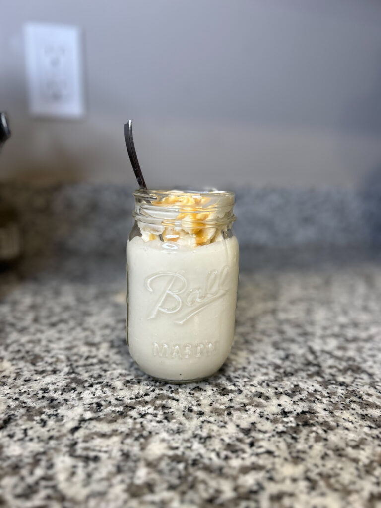 milk kefir in a mason jar with a spoon whipped cream and caramel syrup
